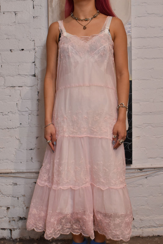 Delicate and feminine design featuring intricate floral embroidery, scalloped straps and hems, and a tulle-accented hemline. Unlined with no pockets or tags, this timeless piece exudes vintage charm and elegance.