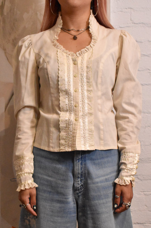 Elegant cream blouse with delicate lace and floral embroidery, capturing the bohemian spirit of the 1970s. A perfect addition for vintage fashion collectors and lovers of timeless pieces.